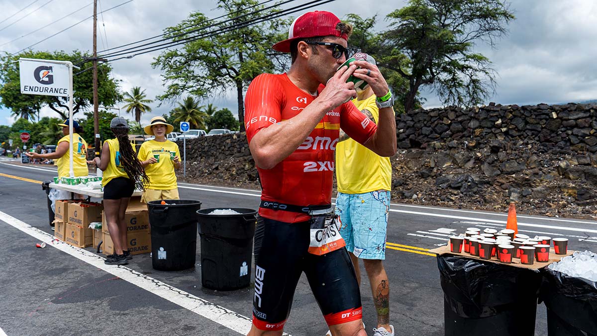 Ironman World Championships Hawai’i 2022 A Male Triathlete Drinks Water At An Aid Station During A Race In Kona Hawaii.