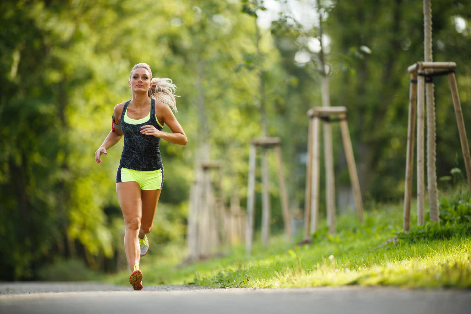 Strength Training For Runners Female Runner Running Along Trail In The Summer With Trees In The Background